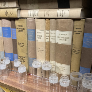 Vintage bound volumes and laboratory glassware on a shelf – set dressing